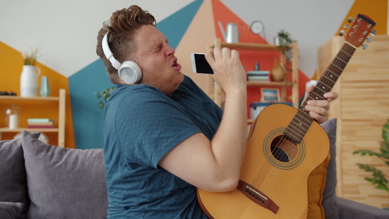 Man practising singing at home with a guitar