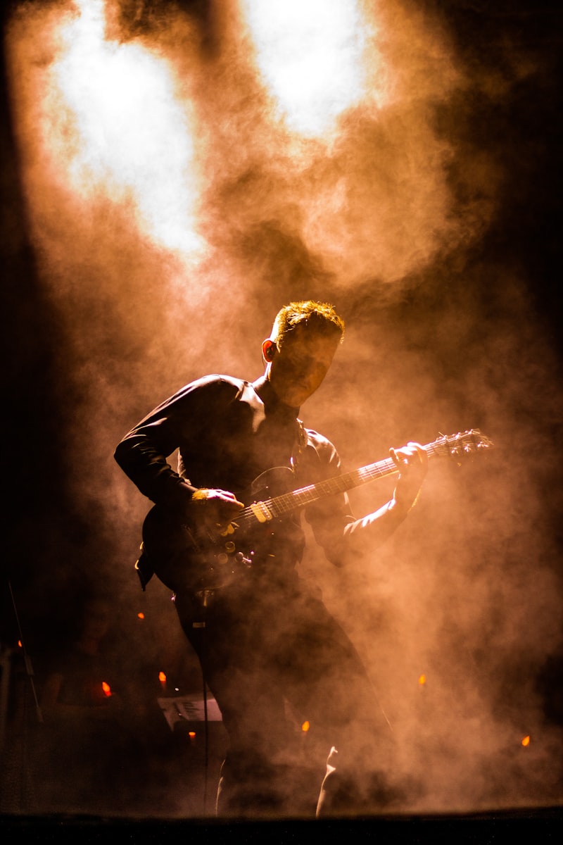 Guitarist silhouetted in warm stage smoke