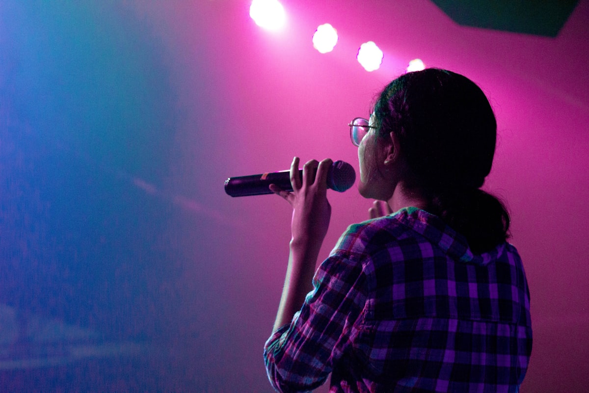 Singer performing on stage under pink lights