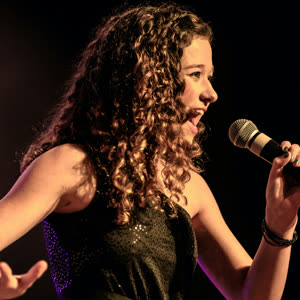 Teen performing on stage with a microphone